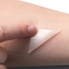 A hand applies a clear hydrocolloid wound care patch to the skin.