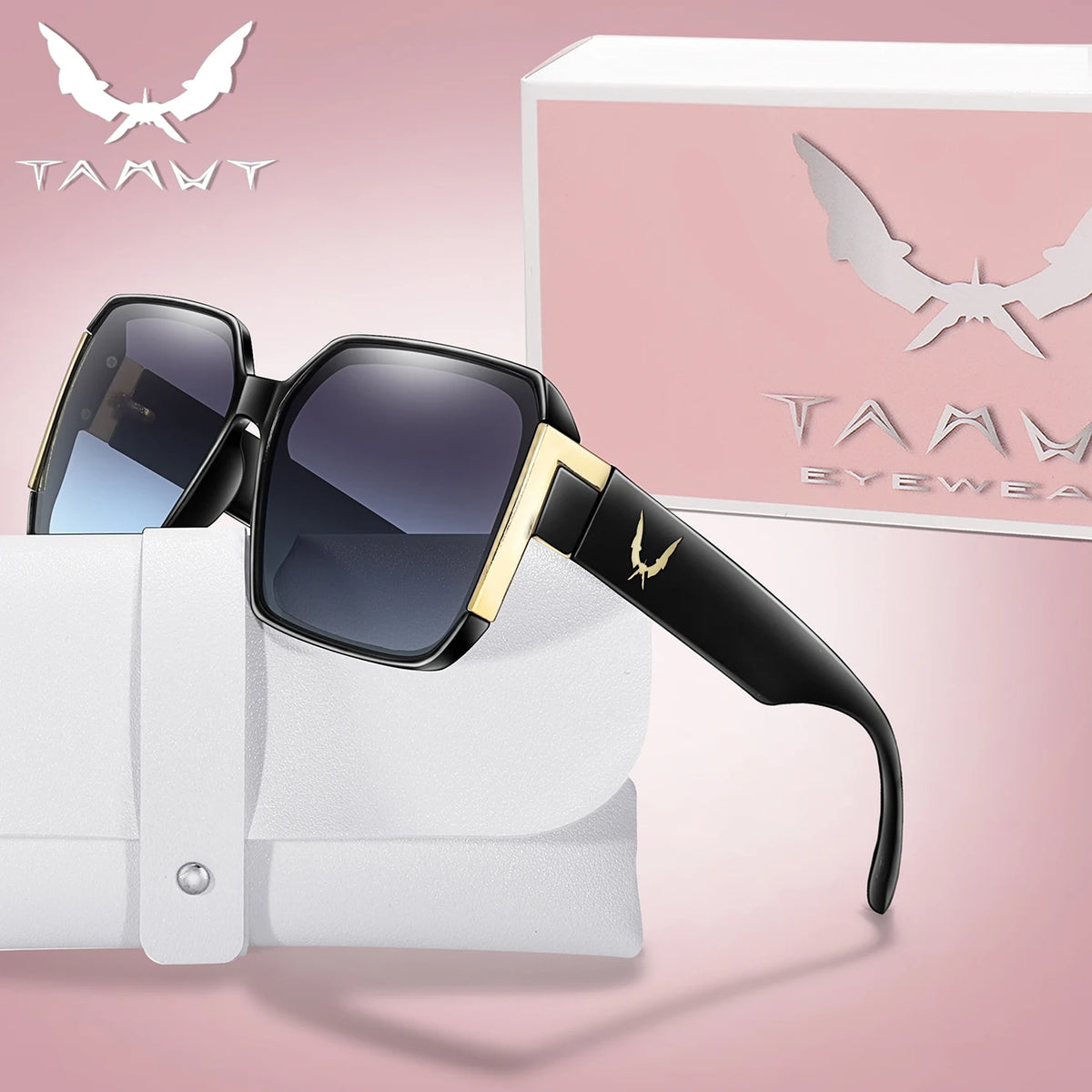 A pair of black and gold trendy square sunglasses resting on a white fabric background with a pink box in the background.