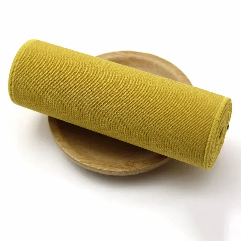 A roll of mustard yellow elastic band resting on a wooden plate.