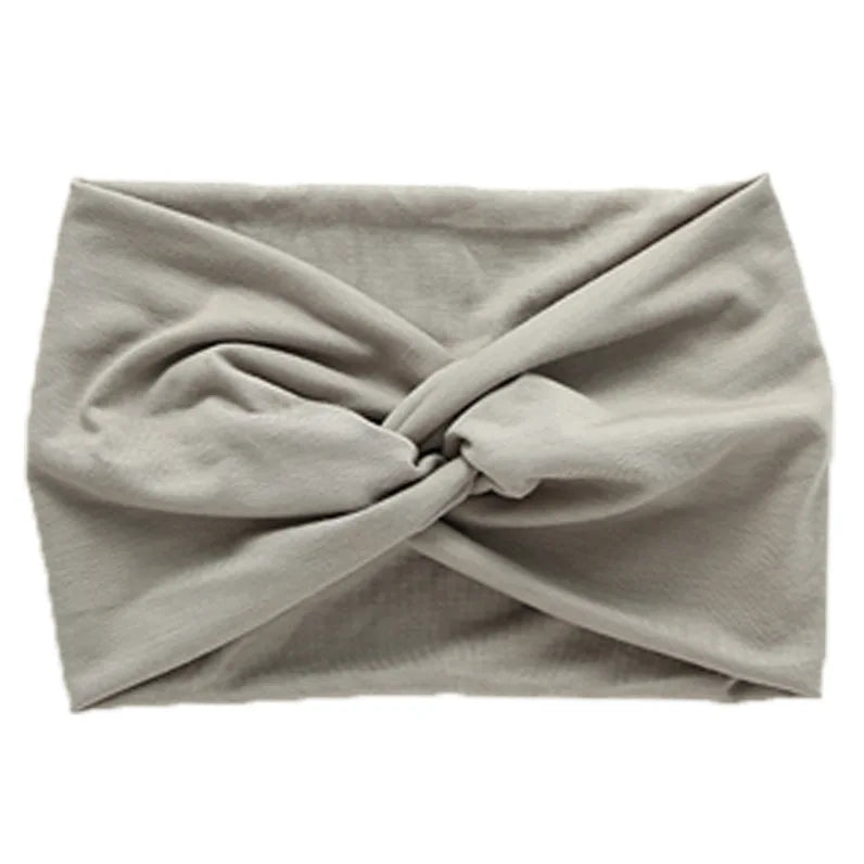 A gray women's elastic sports headband tied in a crisscross knot.