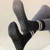Un par de calcetines de yoga negros estampados puestos en el pie de una persona.
