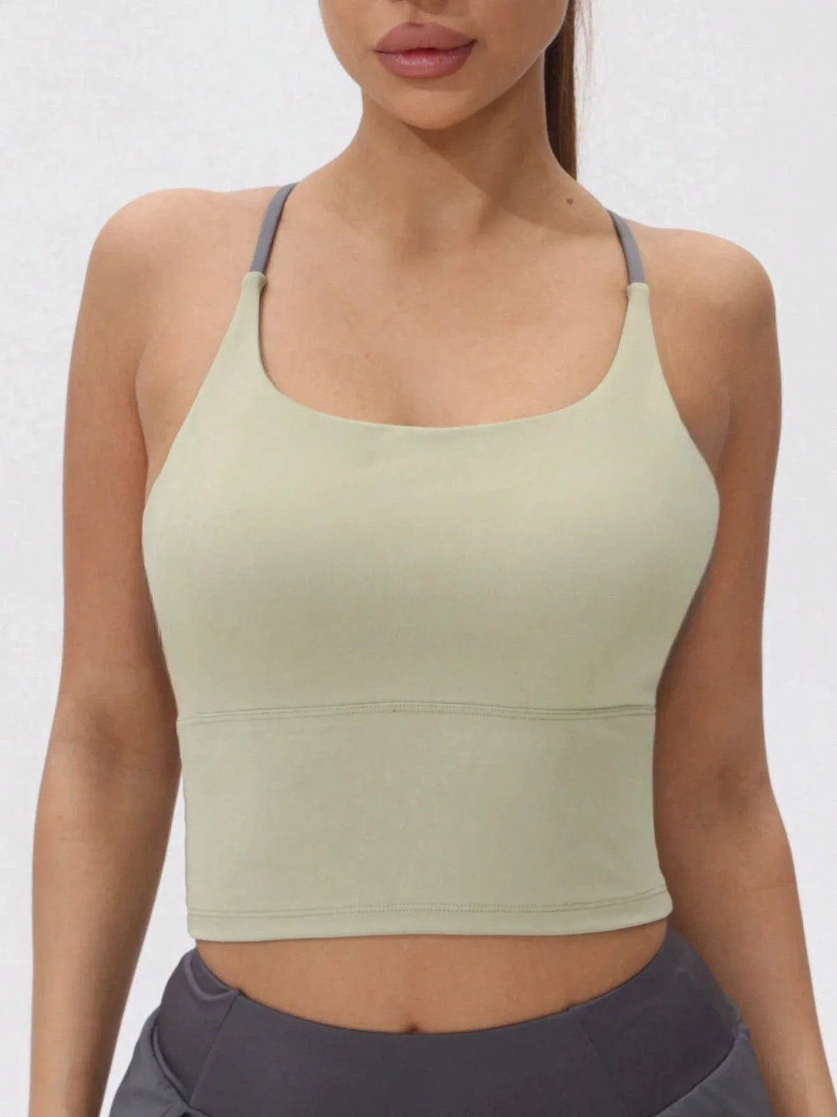A model wearing a light olive green women's athletic crisscross tank top.