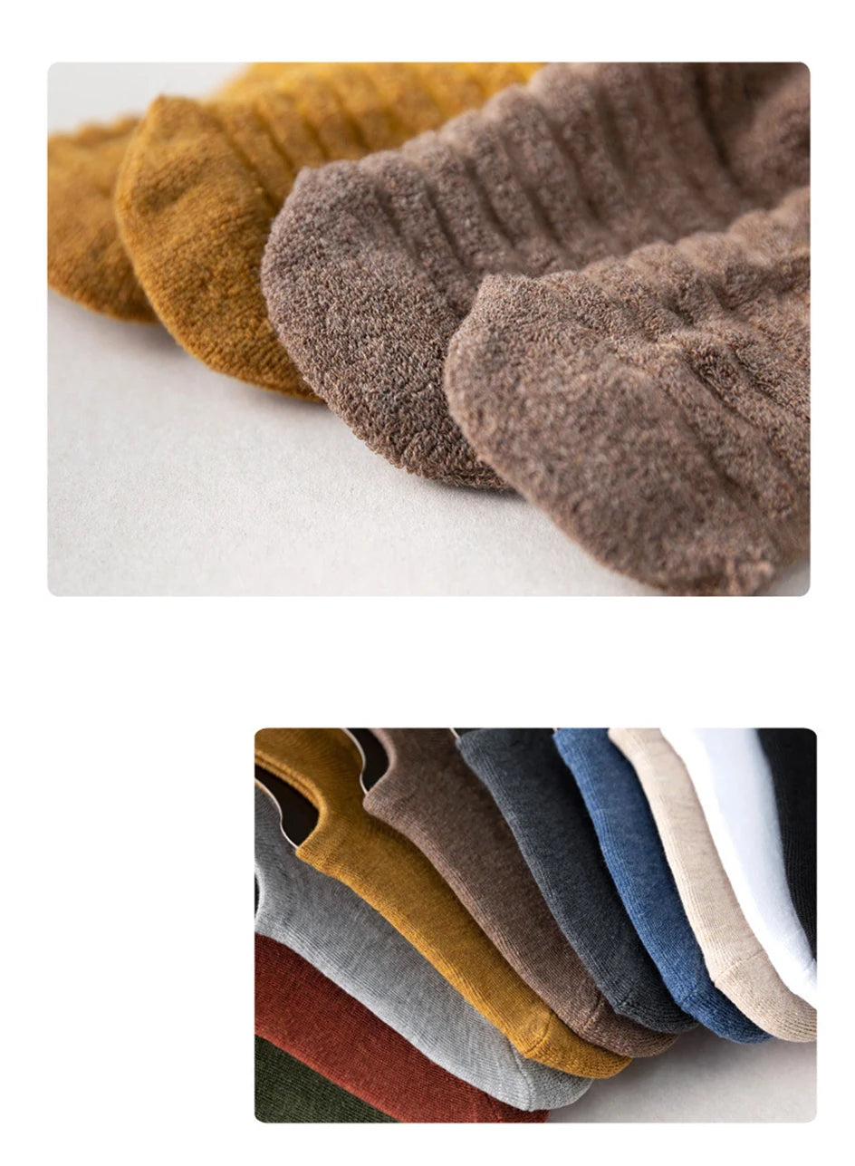 A close-up of various men's cotton crew socks in earthy tones including mustard yellow, brown, gray, and navy blue.