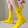 A close-up of bright yellow men's athletic crew socks with an embroidered logo, shown on a person's foot.
