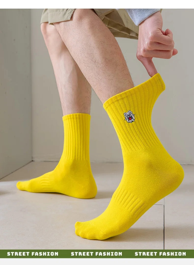 A close-up of bright yellow men's athletic crew socks with an embroidered logo, shown on a person's foot.
