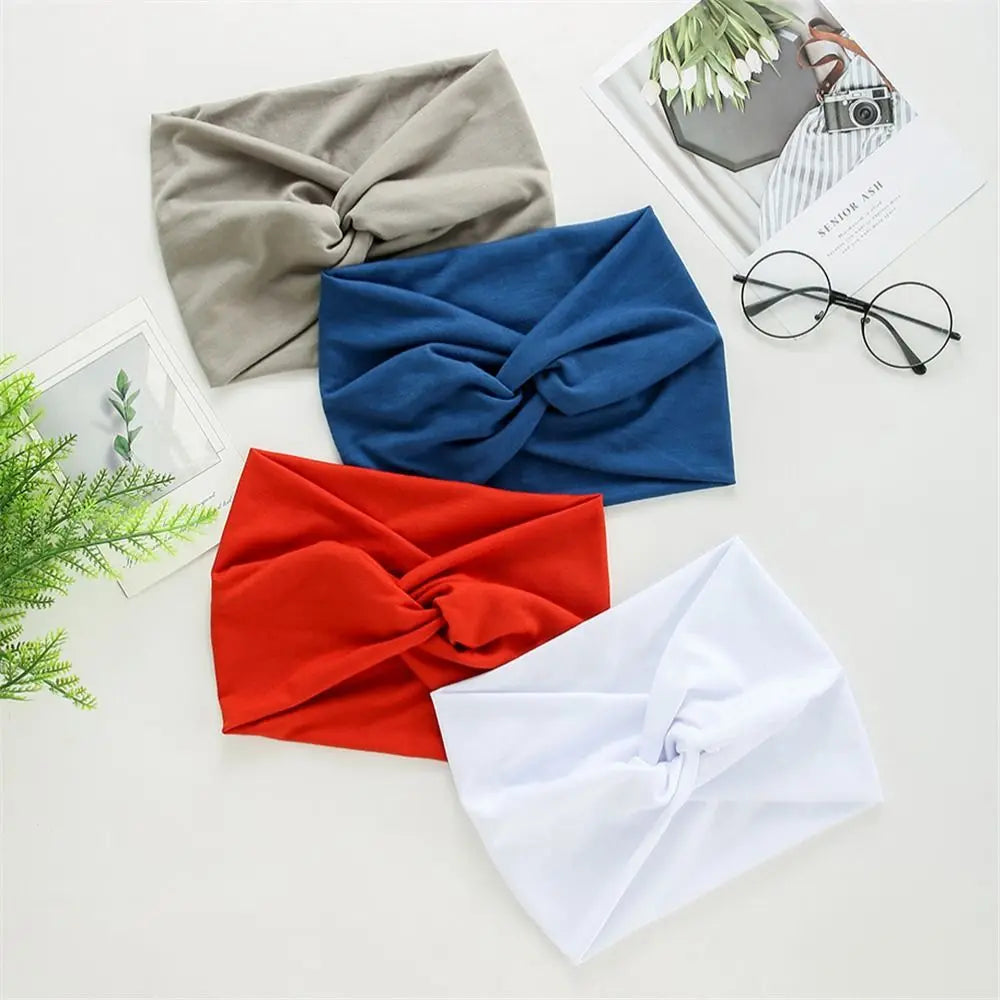 Collection de bandeaux de tête en tissu pliés gris, bleu, rouge et blanc, présentés sur une surface claire.
