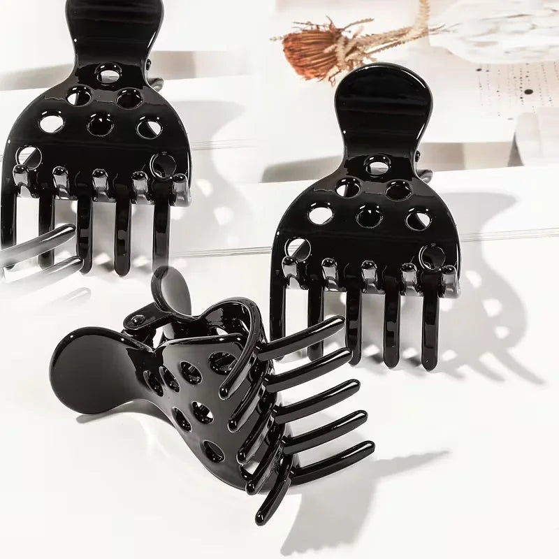 A set of black root lifting hairpin curling clamps with various prong shapes displayed on a white surface.