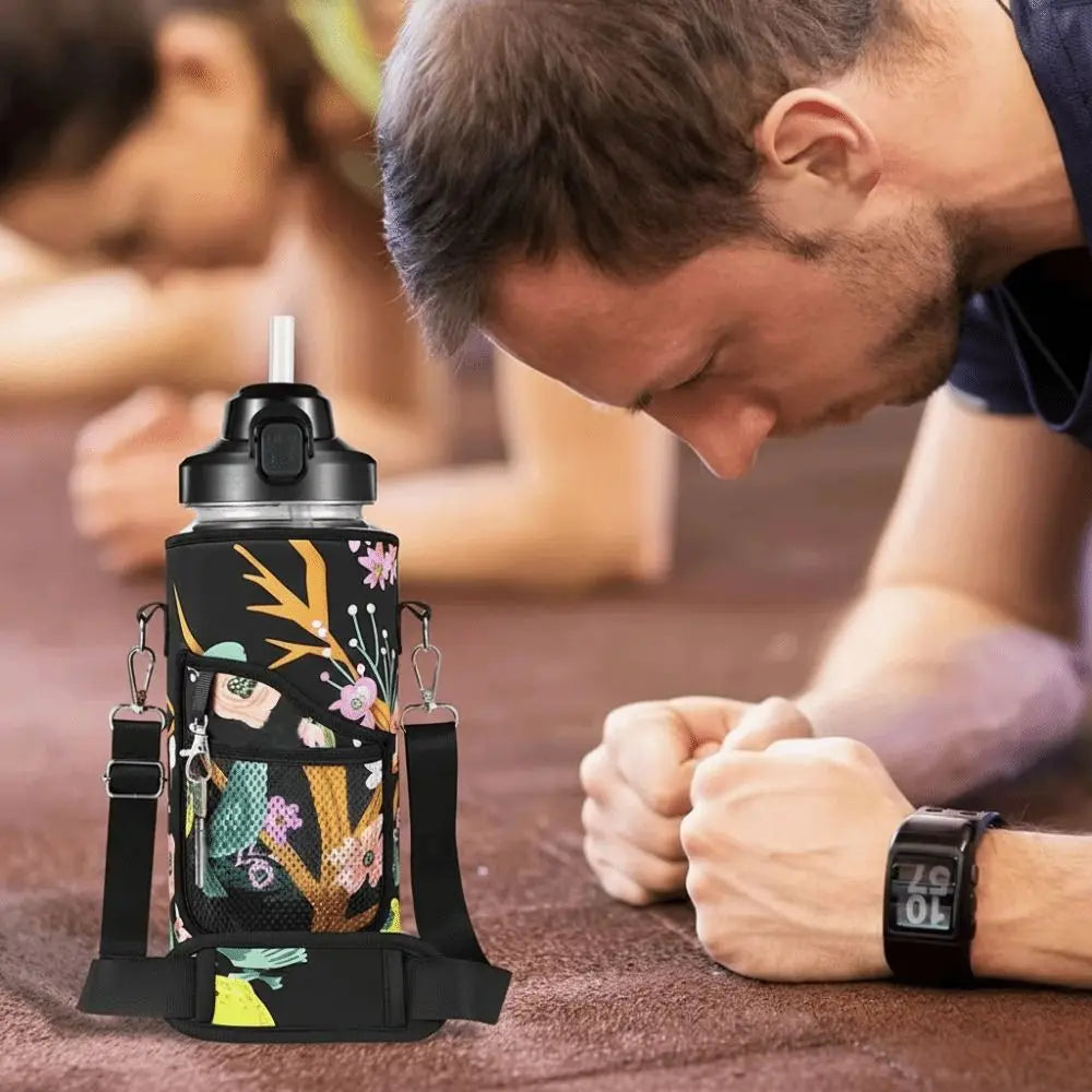 A black insulated water bottle cover with a floral pattern and adjustable strap resting on a wooden surface.