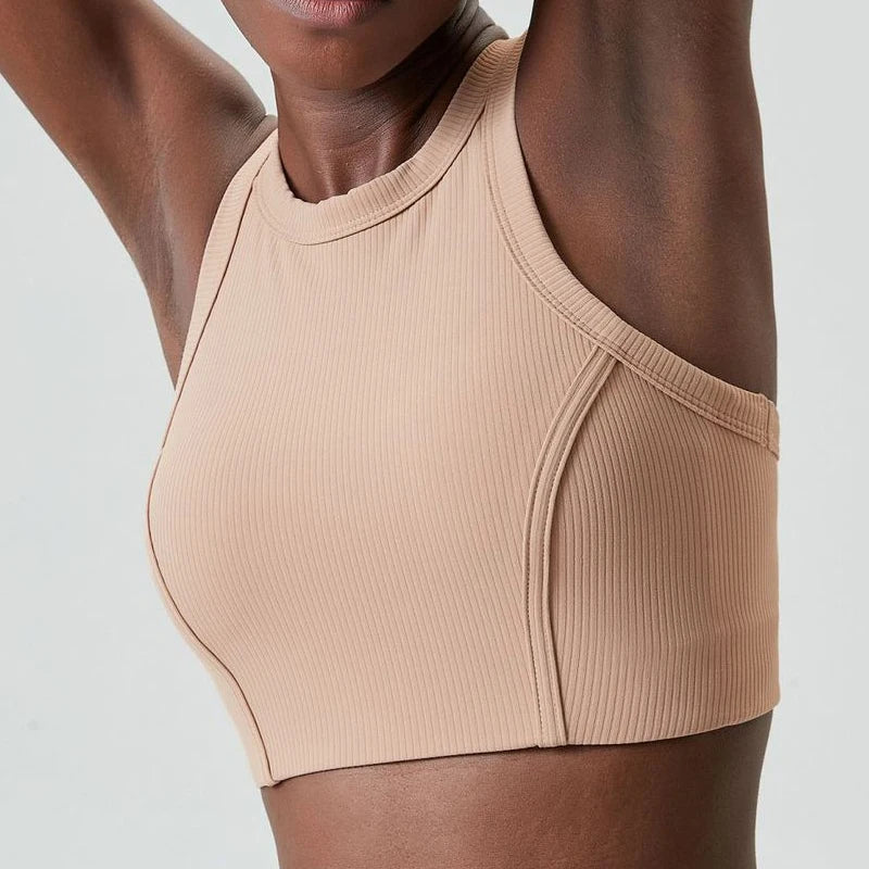 A beige high-impact stretch yoga crop top worn by a person.