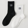 A pair of black and white crew socks featuring the number 23 on the foot.
