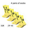 Four pairs of yellow athletic soccer socks with black non-slip grips displayed together.