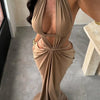 A model wearing a beige elegant maxi dress with a draped cut-out back, shown from the side.
