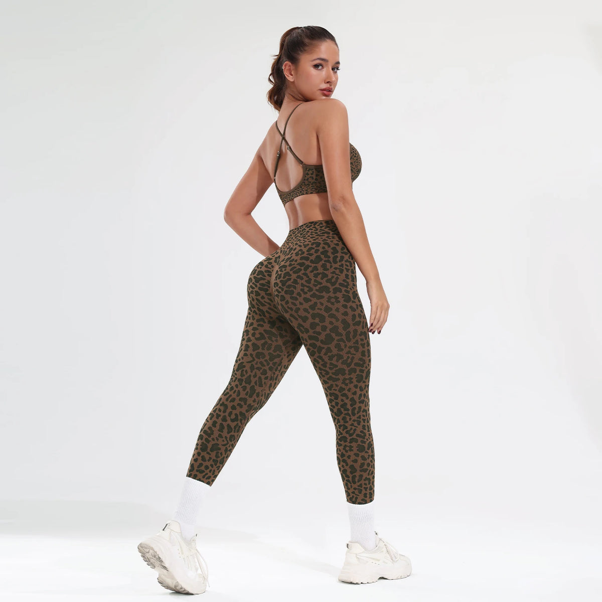 A model wearing a leopard print seamless two-piece sports set consisting of a crop top and leggings.
