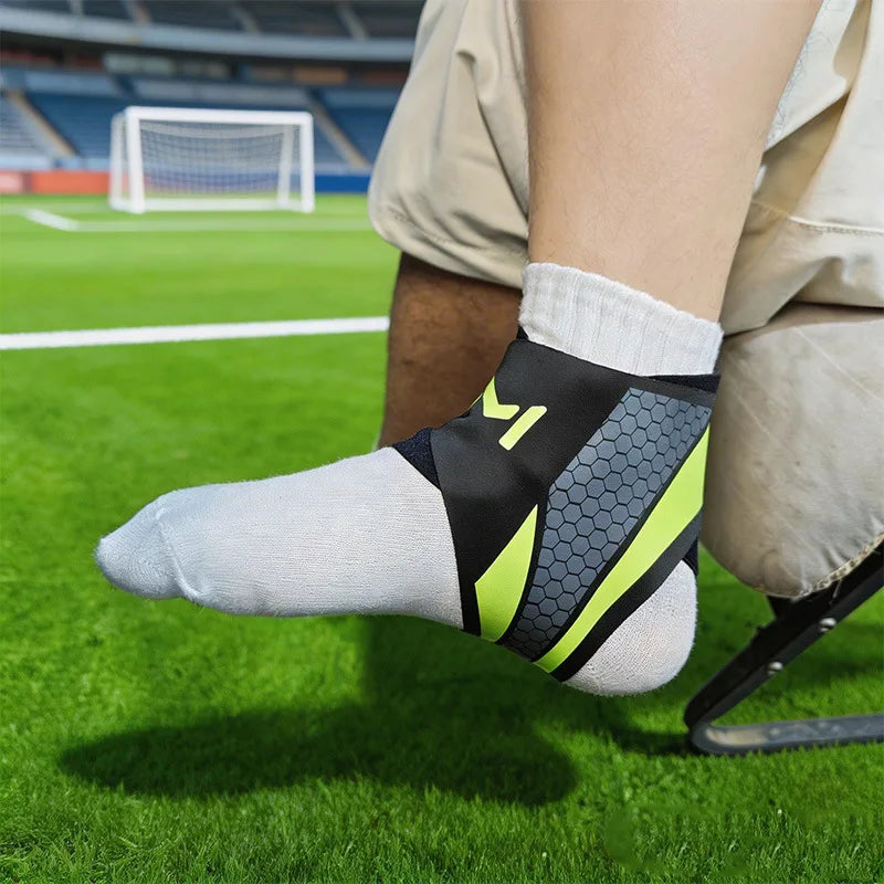 A close-up of a person wearing a black and neon yellow knit ankle brace on their foot while playing on a green sports field.