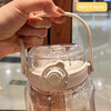 A hand is holding a clear water bottle with a lid and straw attachment, demonstrating the product.