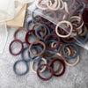 A pile of 50 pieces of mixed color elastic hair bands in various shades of brown, gray, and burgundy.