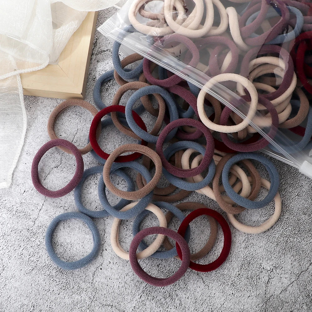 A pile of 50 pieces of mixed color elastic hair bands in various shades of brown, gray, and burgundy.