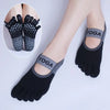 Black silicone yoga socks with a yoga logo on the toe and ankle, shown on a foot.