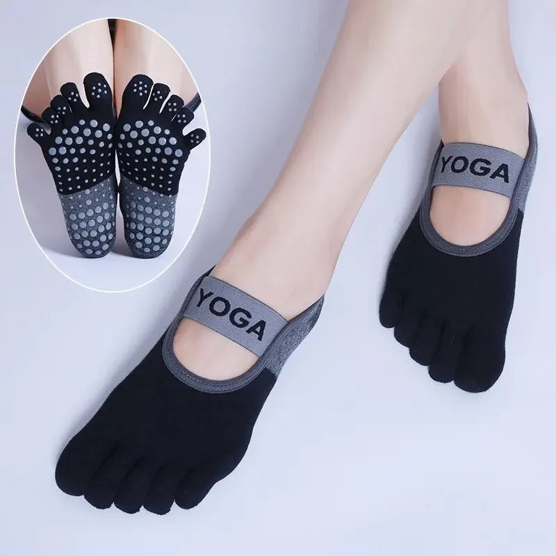 Black silicone yoga socks with a yoga logo on the toe and ankle, shown on a foot.