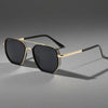 Classic retro square sunglasses with gold-toned metal frames and black lenses resting on a gray surface.