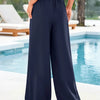 Navy blue flowy high waist drawstring wide leg pants worn by a person outdoors near a pool