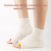 A pair of white and colorful five-finger yoga socks worn on a person's foot.
