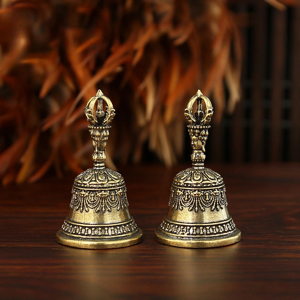 Une paire de cloches ou de maracas en bronze orné avec des ornements, posées sur une surface en bois sombre.
