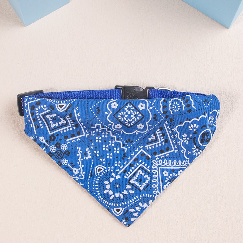 A blue patterned bandana or scarf for pets with a black adjustable clip.