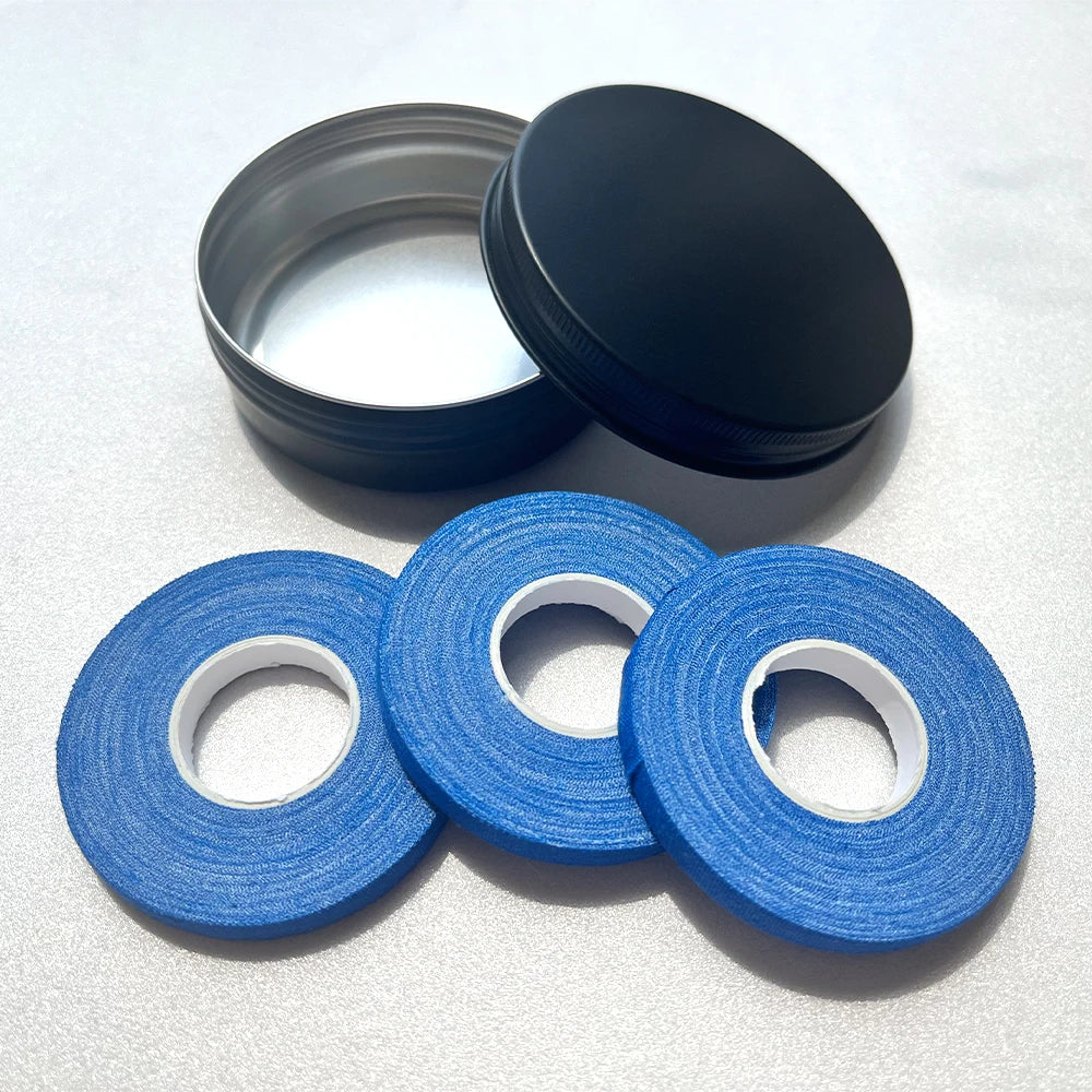Deux couvercles noirs ronds et trois bandes élastiques bleues sont présentés sur une surface blanche.