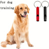 A golden retriever dog is sitting next to a red and black whistle keychain.