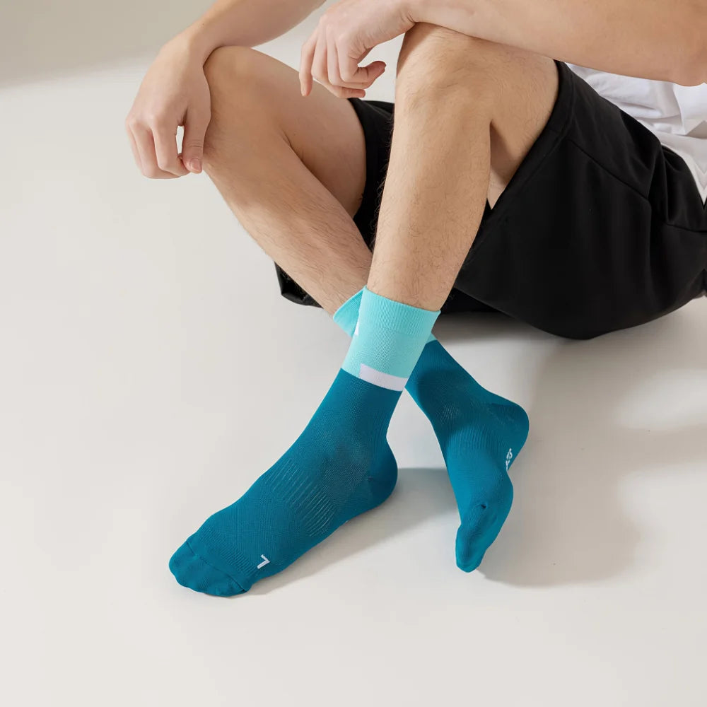 A pair of teal performance athletic running socks worn on a person's foot and ankle.