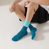 A pair of teal performance athletic running socks worn on a person's foot and ankle.
