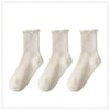 A set of three white cotton ankle socks with ruffled edges.