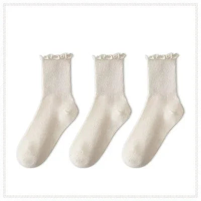 A set of three white cotton ankle socks with ruffled edges.