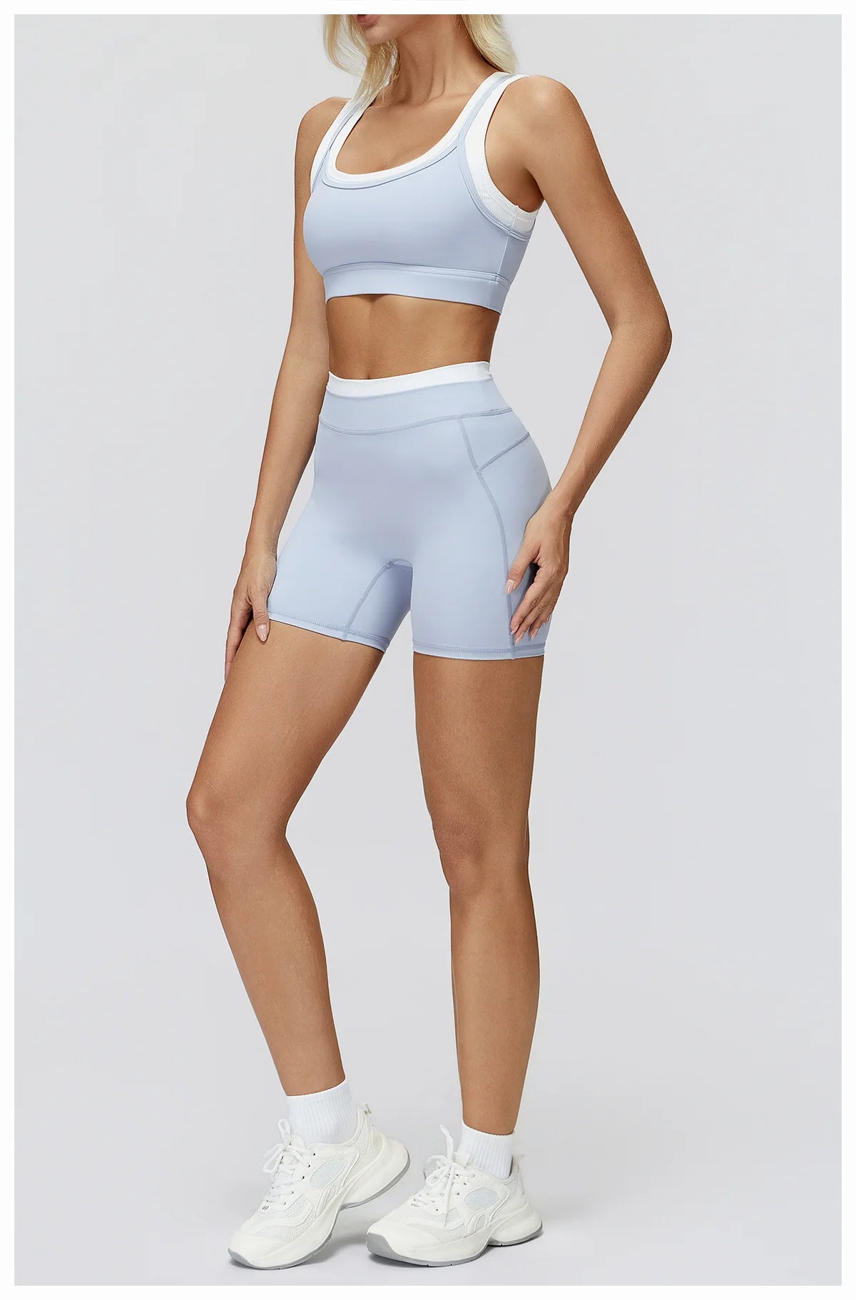 Eine Frau modelliert ein hellblaues zweiteiliges Yoga- und Sportanzug-Set mit Crop-Top und passenden Shorts.