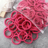 A pile of pink and red elastic hair bands is displayed on a gray surface.