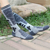 Calcetines térmicos de lana merino gris con diseño estampado sobre una superficie de piedra.