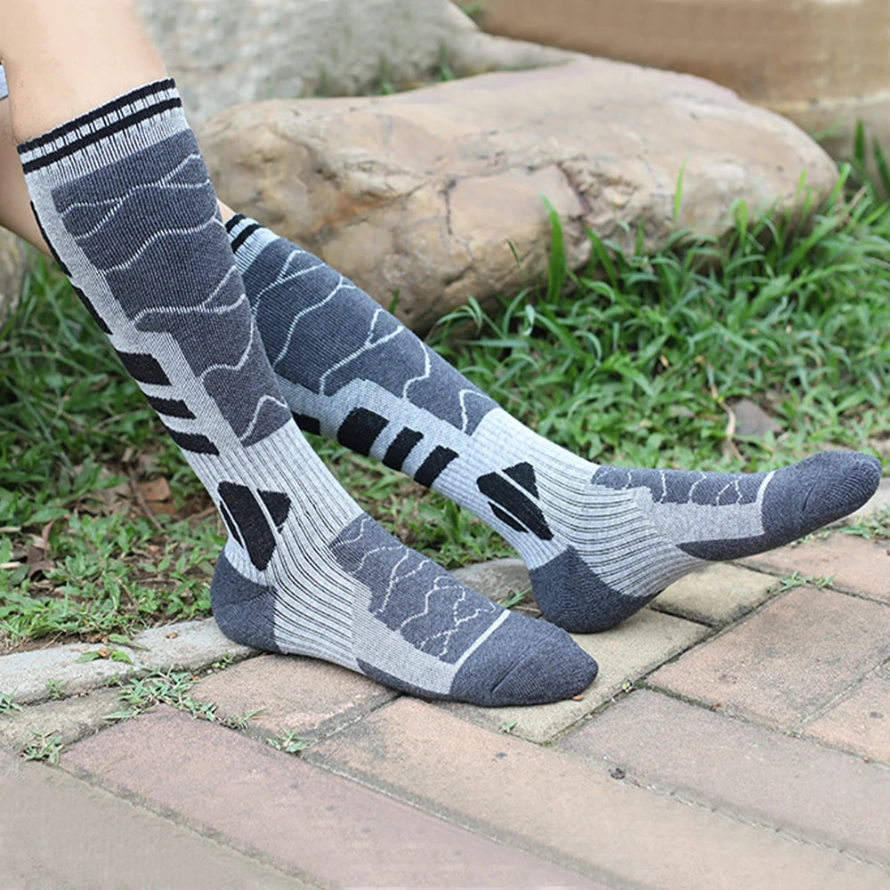 Calcetines térmicos de lana merino gris con diseño estampado sobre una superficie de piedra.