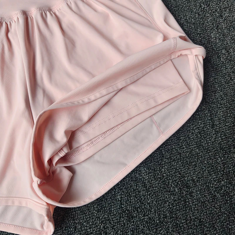 Light pink women's high-waist yoga and fitness shorts folded on a dark gray surface.
