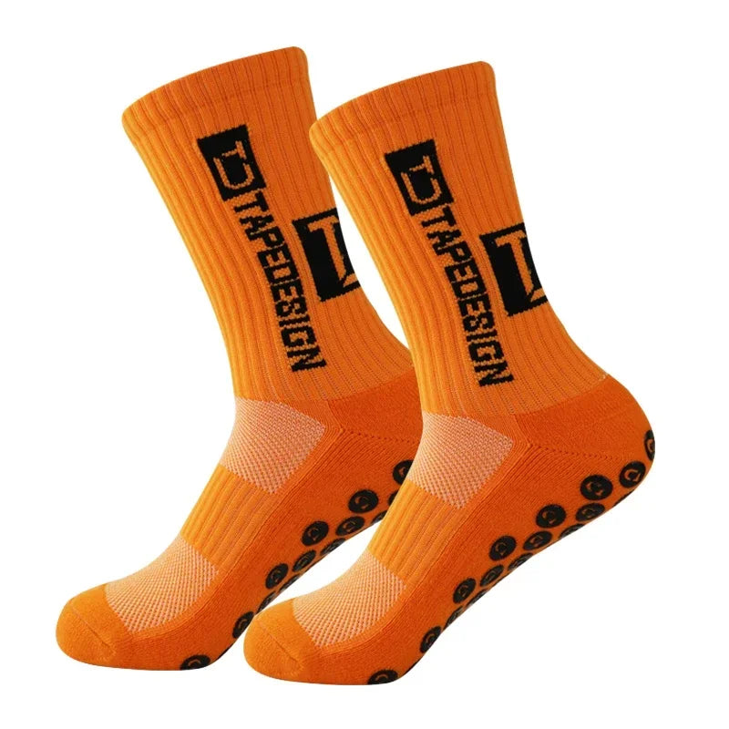 A pair of orange anti-slip performance sports socks with black text and textured soles.