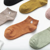 A collection of various colored and embroidered cotton socks laid out on a white background.