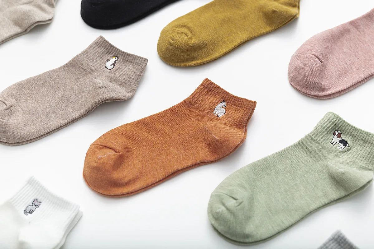 A collection of various colored and embroidered cotton socks laid out on a white background.