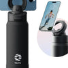 A black insulated sports water bottle with a magnetic lid is shown next to a smartphone displaying a picture of a person jump