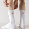 White crew socks with heart embroidery worn on a person's leg.