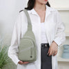 Eine Frau hält eine hellgrüne strapazierfähige Crossbody-Messenger-Tasche vor einem weißen Hemd und einem dunklen Rock.
