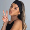 Une femme aux longs cheveux blonds portant un bandeau élastique noir, faisant un signe de paix.