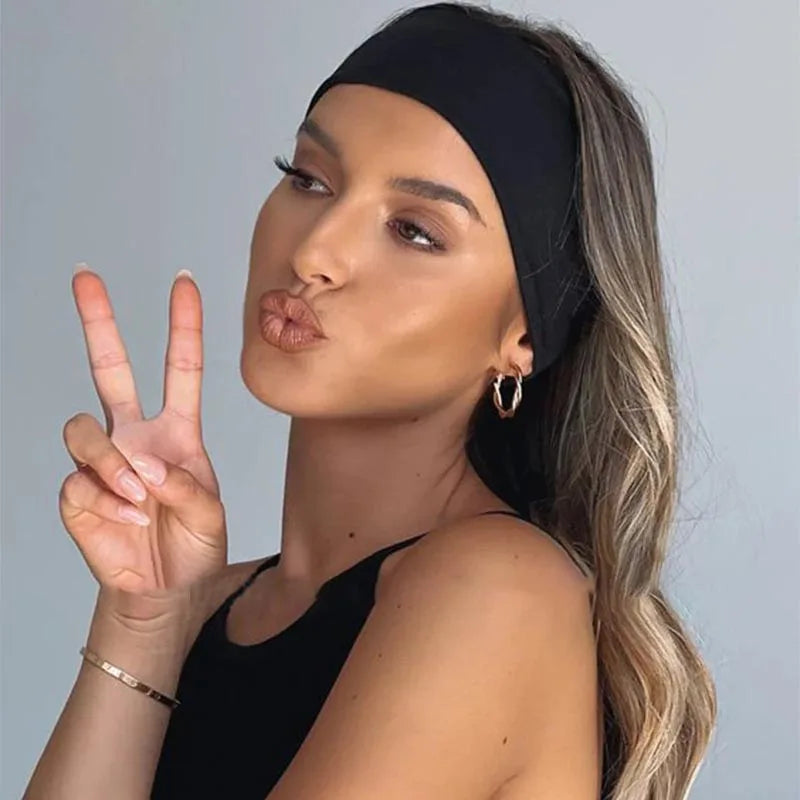 Une femme aux longs cheveux blonds portant un bandeau élastique noir, faisant un signe de paix.