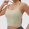 A model wearing a light olive green women's athletic crisscross tank top and dark gray athletic bottoms.