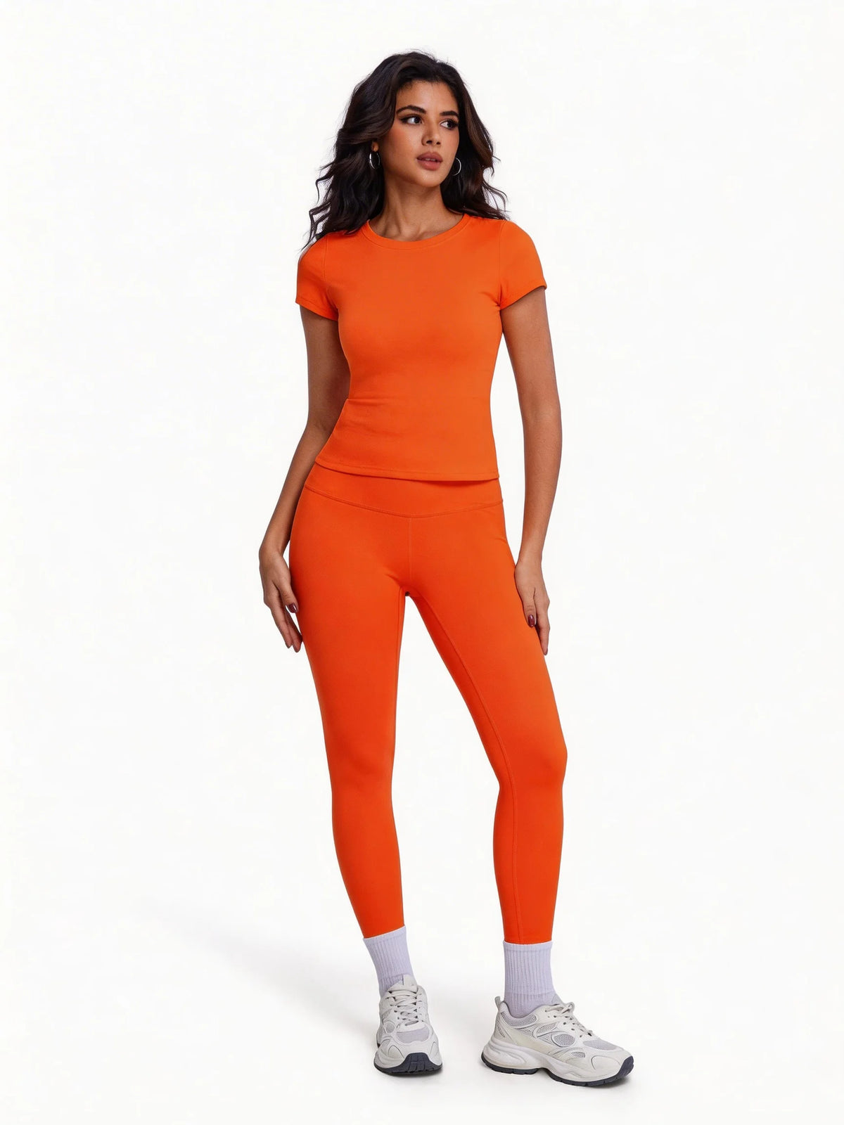 Una mujer modela un conjunto de yoga naranja sin costuras de tiro alto con top de manga corta y leggings largos.