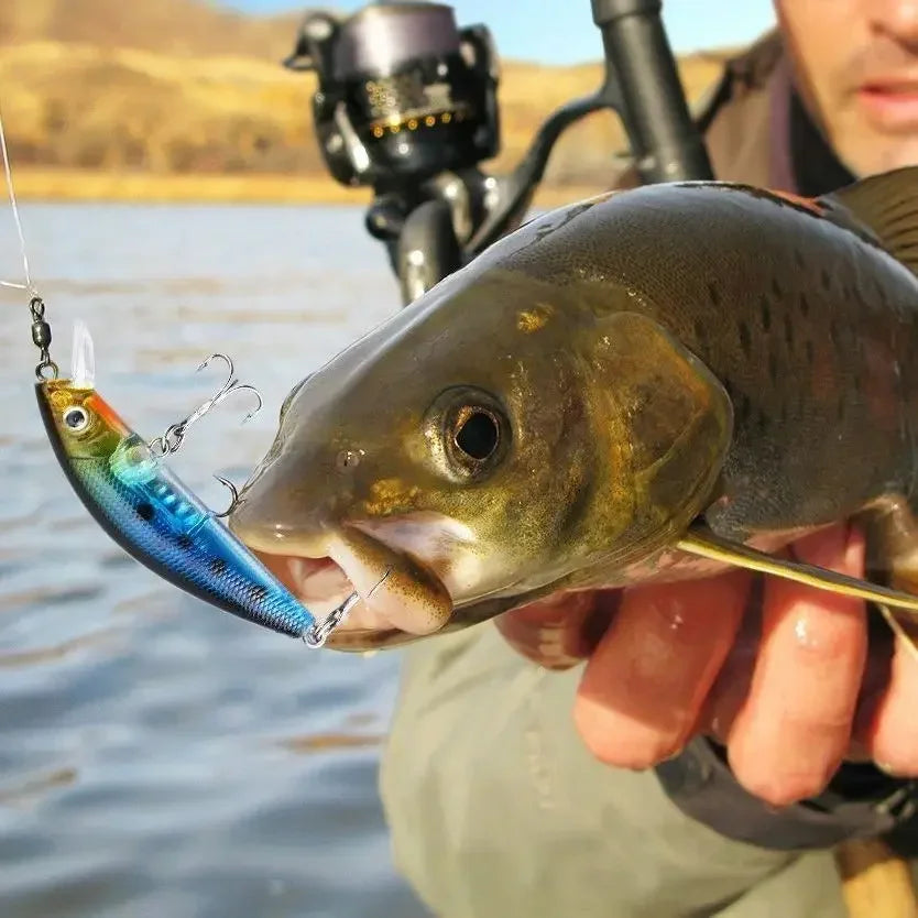 A hand holds a fish caught on a fishing line, featuring a multi-function fishing lure kit set.